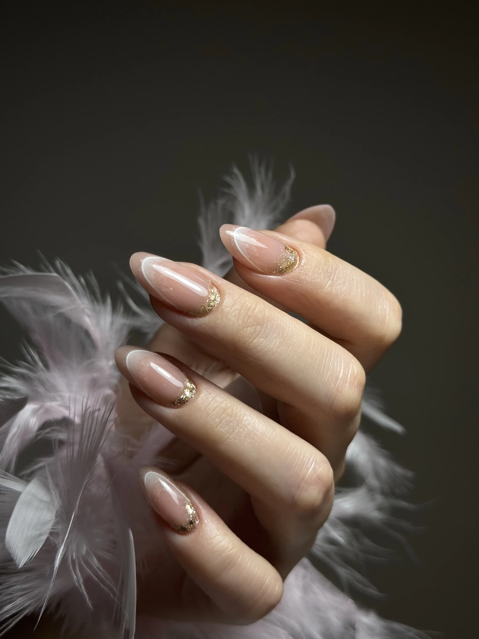 Nude almond manicure with white French details and gold accents by Ruta Beauty