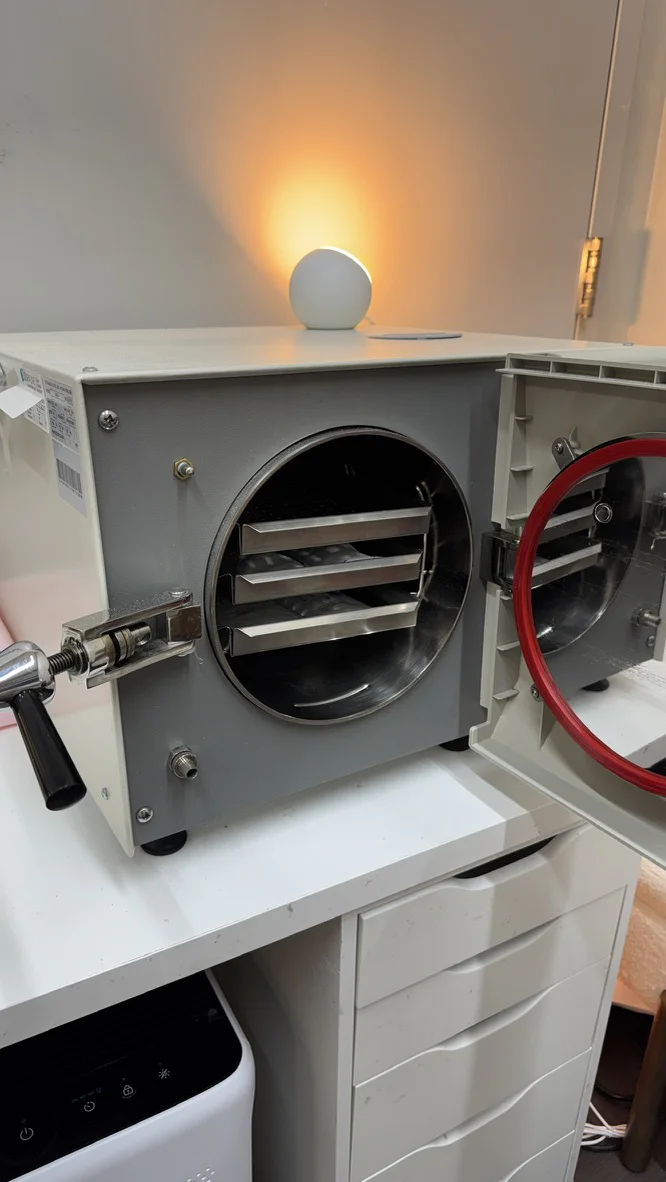 Open autoclave with instrument trays at Ruta Beauty